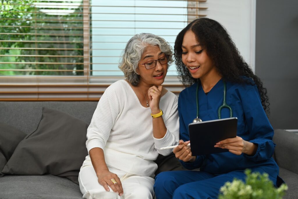 Female doctor holding digital tablet and explaining medicine dosage to elder woman.